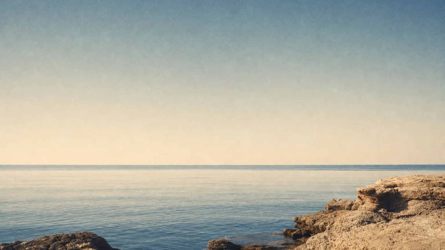 Clear turquoise Aegean water meeting a pale rocky coastline